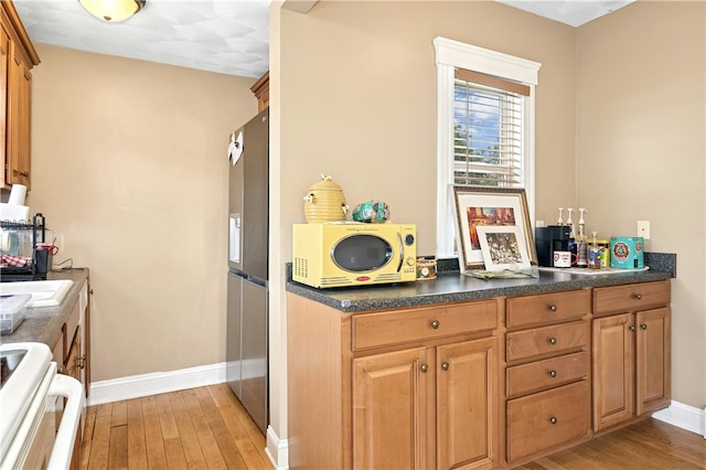 79 Winthrop St, Woonsocket, RI 02895 - kitchen with stove, light wood-style flooring, dark countertops, and stainless steel refrigerator with ice dispenser