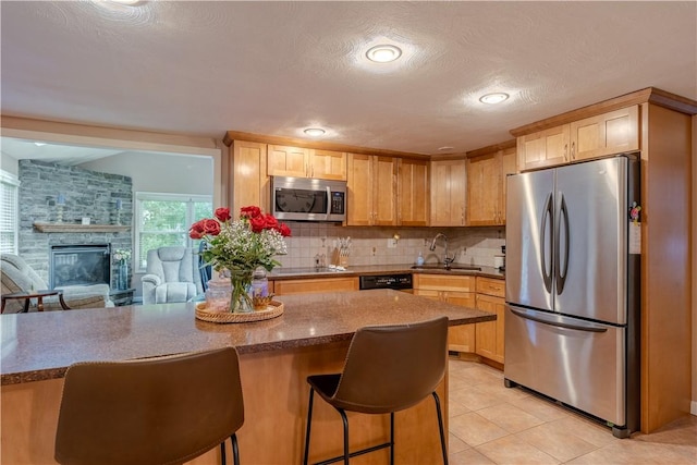 6 Jacksonia Dr, North Providence, RI 02911 - kitchen with black appliances, a kitchen bar, light brown cabinets, backsplash, and light tile patterned floors