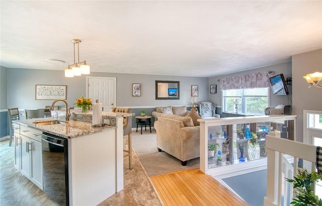 350 Narrow Ln, Charlestown, RI 02813 - kitchen featuring black dishwasher, an island with sink, light stone countertops, hanging light fixtures, and open floor plan