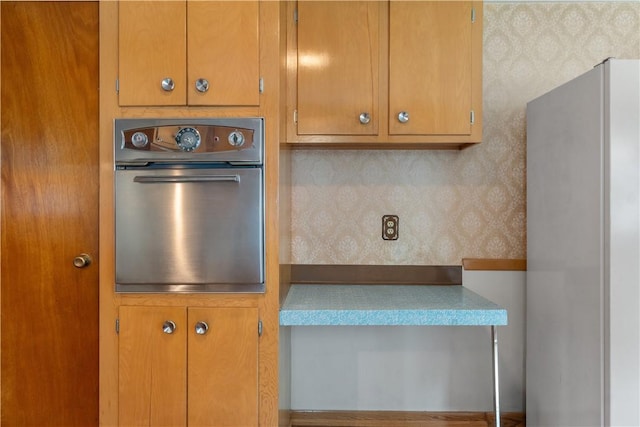 352 Cove Ave, Warwick, RI 02886 - kitchen featuring oven, freestanding refrigerator, wallpapered walls, and brown cabinets