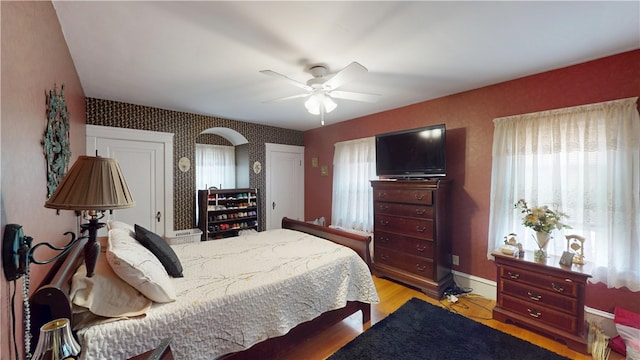 95 Burlington St, Providence, RI 02906 - bedroom with multiple windows, light wood finished floors, wallpapered walls, a ceiling fan, and arched walkways