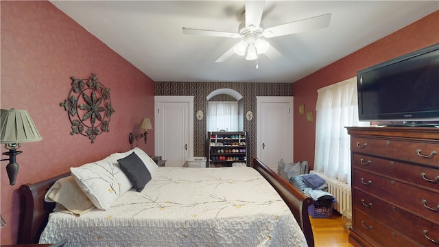 95 Burlington St, Providence, RI 02906 - bedroom featuring wallpapered walls, light wood-type flooring, an accent wall, radiator heating unit, and a ceiling fan