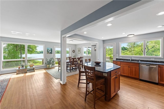 106 Lauri Dr, Charlestown, RI 02813 - kitchen with stainless steel dishwasher, wood finished floors, a kitchen breakfast bar, dark stone countertops, and brown cabinets