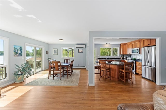 106 Lauri Dr, Charlestown, RI 02813 - dining space with an AC wall unit, plenty of natural light, light wood-style floors, and a baseboard radiator