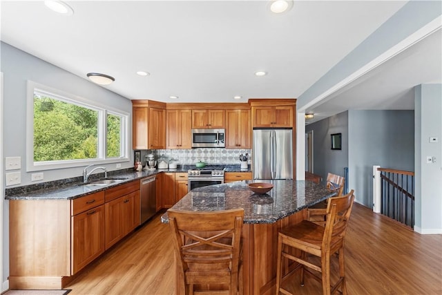 106 Lauri Dr, Charlestown, RI 02813 - kitchen featuring appliances with stainless steel finishes, light wood-style floors, dark stone counters, a breakfast bar area, and a center island