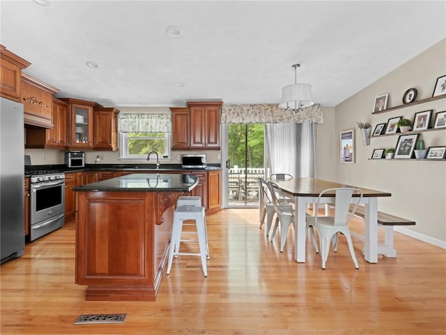 15 Sycamore Dr, West Warwick, RI 02893 - kitchen with stainless steel appliances, brown cabinetry, light wood-style flooring, a kitchen breakfast bar, and a kitchen island