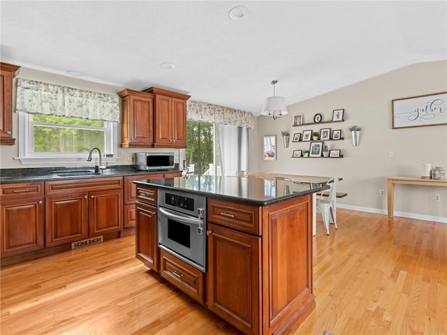 15 Sycamore Dr, West Warwick, RI 02893 - kitchen featuring appliances with stainless steel finishes, light wood-style flooring, a kitchen island, lofted ceiling, and brown cabinetry