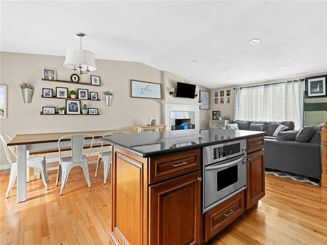 15 Sycamore Dr, West Warwick, RI 02893 - kitchen with stainless steel oven, light wood-type flooring, open floor plan, lofted ceiling, and dark stone countertops