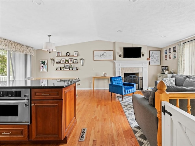 15 Sycamore Dr, West Warwick, RI 02893 - kitchen with oven, vaulted ceiling, a fireplace, open floor plan, and light wood finished floors