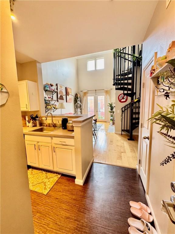 1000 Providence Pl Unit 449, Providence, RI 02903 - kitchen featuring wood finished floors, a peninsula, a towering ceiling, french doors, and light countertops