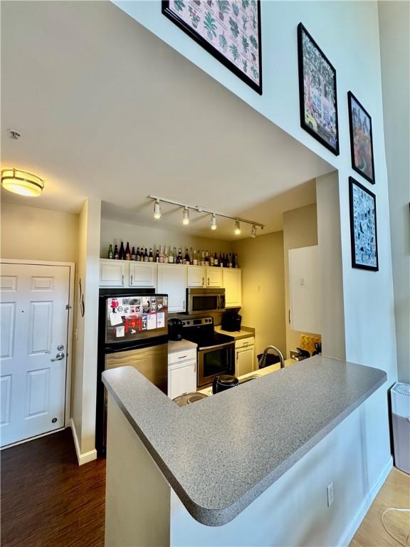 1000 Providence Pl Unit 449, Providence, RI 02903 - kitchen with stainless steel appliances, a peninsula, track lighting, white cabinets, and dark wood-style flooring