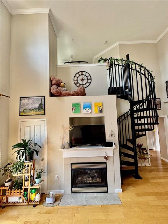 1000 Providence Pl Unit 449, Providence, RI 02903 - living room featuring wood finished floors, ornamental molding, a tile fireplace, and stairs