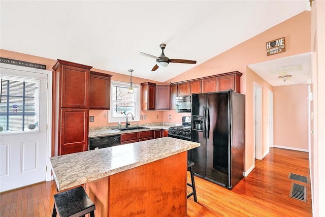 28 Plant St, Cumberland, RI 02864 - kitchen with black appliances, a kitchen breakfast bar, lofted ceiling, light wood-style flooring, and a ceiling fan