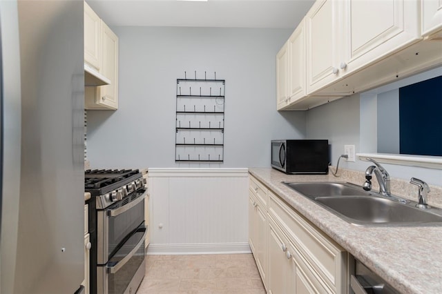 750 Quaker Ln Unit B112, Warwick, RI 02818 - kitchen with stainless steel appliances, under cabinet range hood, light countertops, wainscoting, and light tile patterned floors