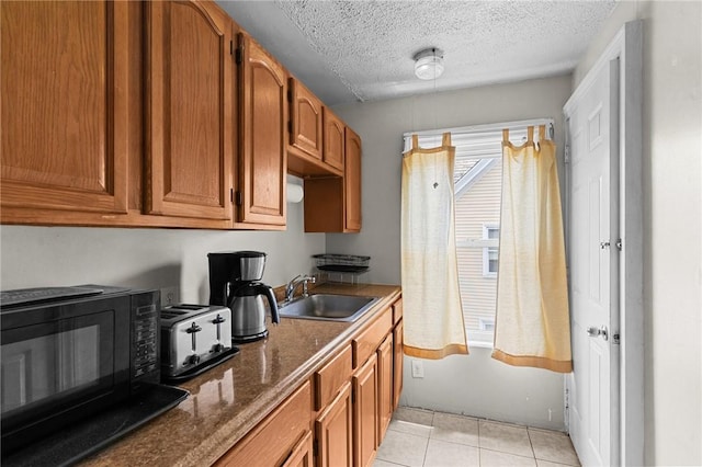 230 Pawtucket Ave, Pawtucket, RI 02860 - kitchen featuring black microwave, brown cabinetry, light tile patterned flooring, a textured ceiling, and dark stone countertops