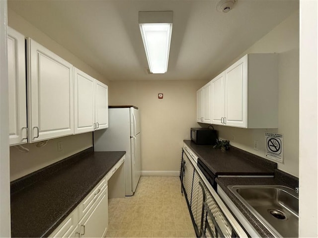 106 Mill St Unit 102, Woonsocket, RI 02895 - kitchen featuring dark countertops, white cabinetry, freestanding refrigerator, and black microwave