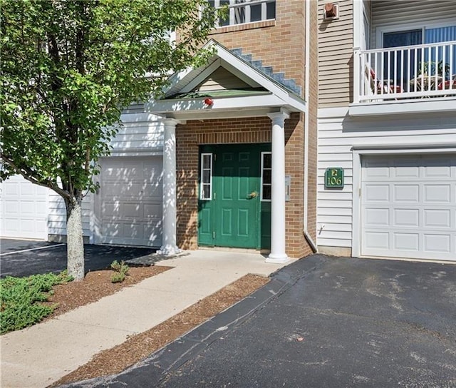 106 Mill St Unit 102, Woonsocket, RI 02895 - view of exterior entry with asphalt driveway, brick siding, and a balcony