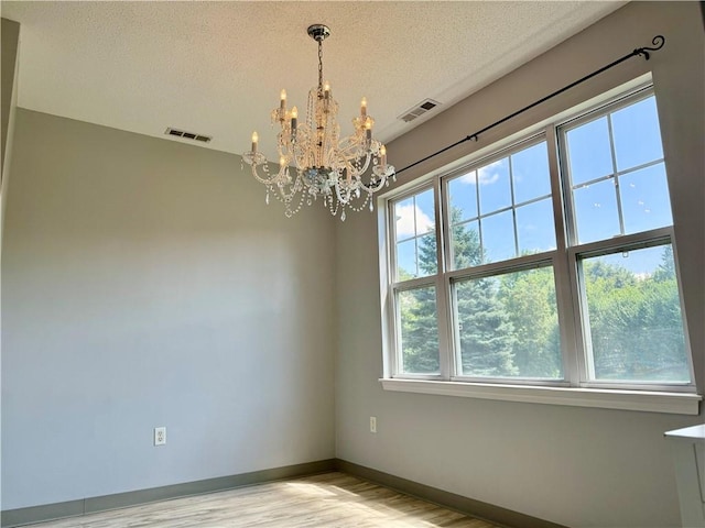 106 Mill St Unit 102, Woonsocket, RI 02895 - empty room with a chandelier, light wood-style floors, and a textured ceiling