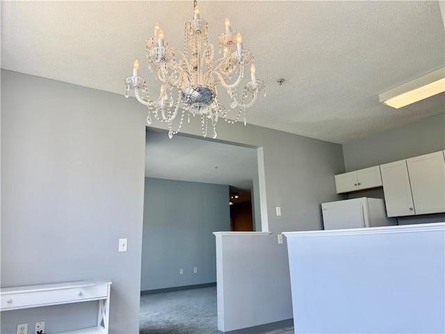 106 Mill St Unit 102, Woonsocket, RI 02895 - kitchen with a textured ceiling, a chandelier, freestanding refrigerator, white cabinetry, and carpet flooring