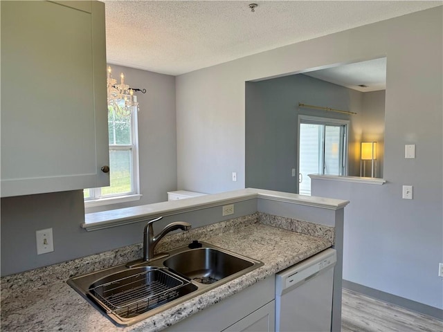 106 Mill St Unit 102, Woonsocket, RI 02895 - kitchen featuring light wood finished floors, white dishwasher, plenty of natural light, a textured ceiling, and white cabinetry