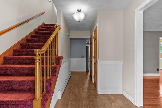 43 Peckham Pl, Bristol, RI 02809 - stairs with a baseboard heating unit, wood finished floors, and a wainscoted wall