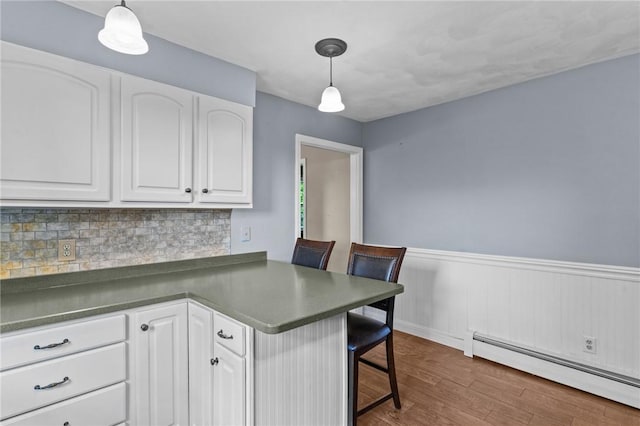 43 Peckham Pl, Bristol, RI 02809 - kitchen featuring a baseboard heating unit, a peninsula, white cabinetry, dark wood finished floors, and a wainscoted wall