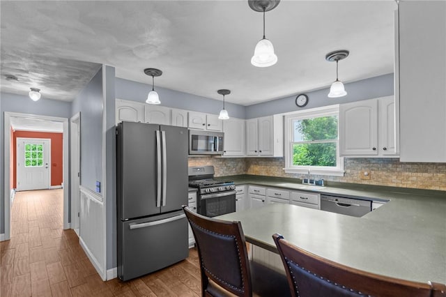 43 Peckham Pl, Bristol, RI 02809 - kitchen featuring appliances with stainless steel finishes, decorative backsplash, a peninsula, and white cabinetry