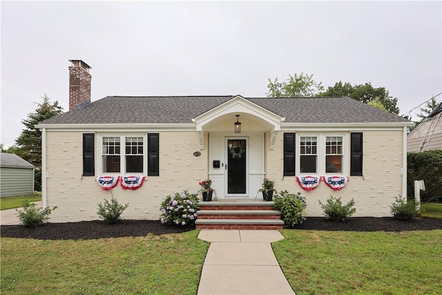 72 Audubon Rd, Warwick, RI 02888 - view of front of house featuring a front yard, a chimney, and brick siding