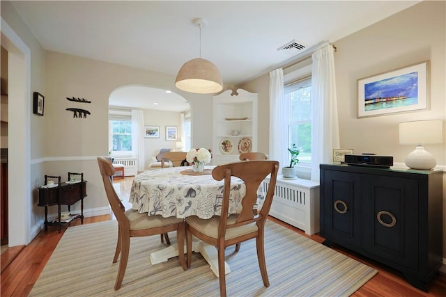 72 Audubon Rd, Warwick, RI 02888 - dining room with radiator, arched walkways, light wood-style floors, and built in features