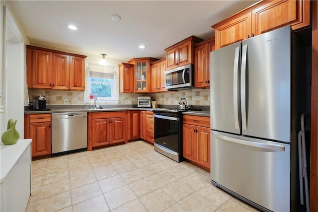 72 Audubon Rd, Warwick, RI 02888 - kitchen with appliances with stainless steel finishes, brown cabinetry, backsplash, dark countertops, and recessed lighting