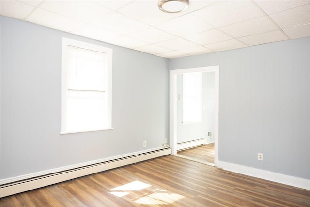 89 Warren Ave, East Providence, RI 02914 - empty room with a drop ceiling, a baseboard heating unit, healthy amount of natural light, and wood finished floors