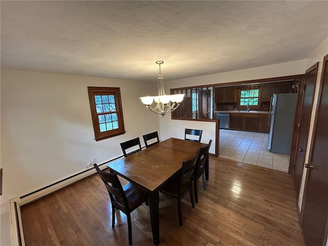 80 Silverwood Ln, West Warwick, RI 02893 - dining space featuring a chandelier, light wood-style flooring, a textured ceiling, and baseboard heating