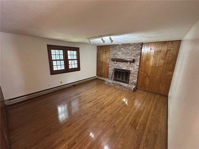 80 Silverwood Ln, West Warwick, RI 02893 - unfurnished living room featuring wood-type flooring, a fireplace, a baseboard radiator, track lighting, and wood walls