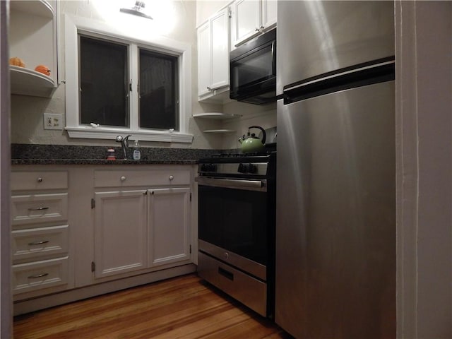 598 Admiral St, Providence, RI 02908 - kitchen featuring appliances with stainless steel finishes, white cabinetry, light wood finished floors, dark stone countertops, and open shelves