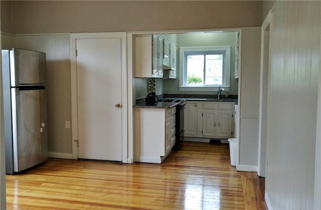 598 Admiral St, Providence, RI 02908 - kitchen featuring freestanding refrigerator, dark countertops, light wood-type flooring, and white cabinetry