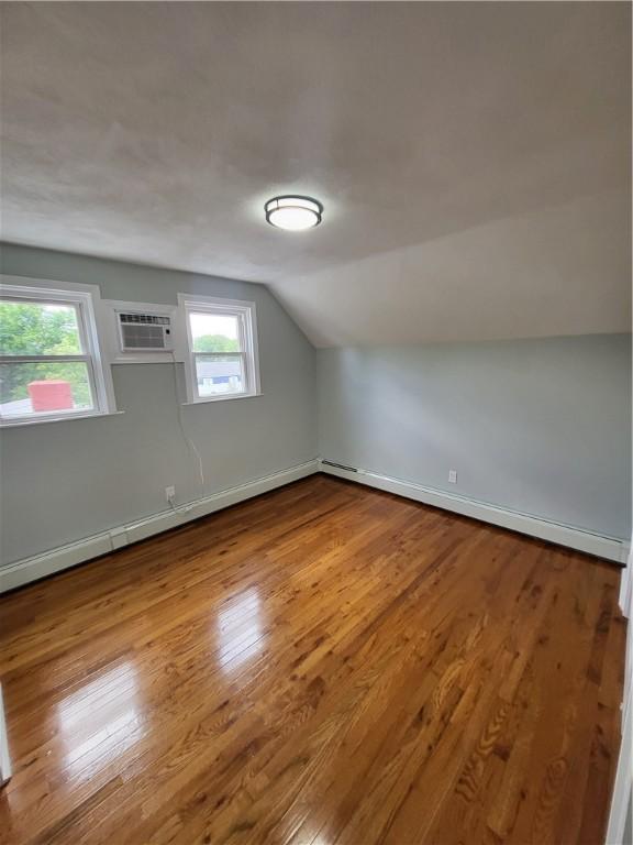 57 Merino St, Johnston, RI 02919 - additional living space with an AC wall unit, vaulted ceiling, and wood finished floors