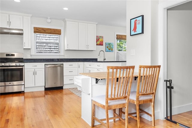 92 Franklin St, Bristol, RI 02809 - kitchen with stainless steel appliances, under cabinet range hood, light wood finished floors, white cabinetry, and recessed lighting