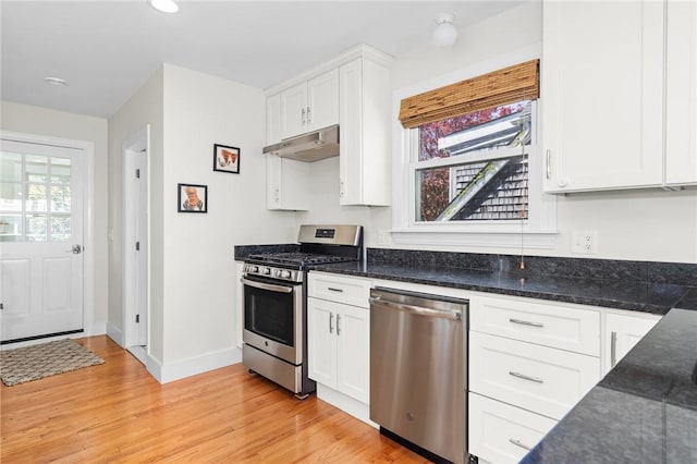 92 Franklin St, Bristol, RI 02809 - kitchen with stainless steel appliances, under cabinet range hood, white cabinets, light wood-style floors, and dark stone counters