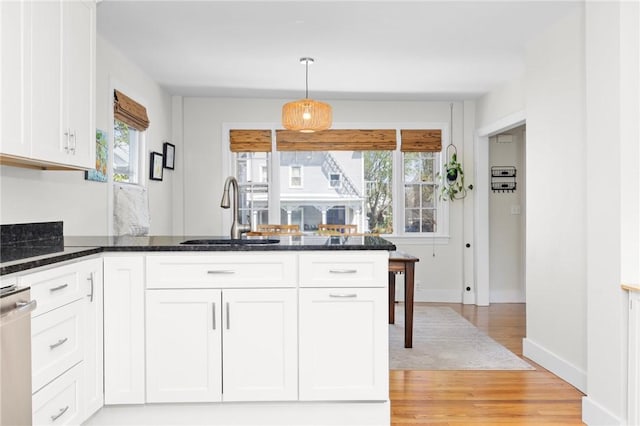 92 Franklin St, Bristol, RI 02809 - kitchen featuring light wood finished floors, dishwasher, dark stone counters, white cabinetry, and a peninsula