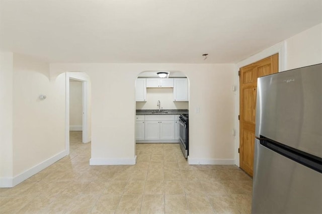 54 Harrison St, Pawtucket, RI 02860 - kitchen featuring freestanding refrigerator, arched walkways, gas range, light tile patterned floors, and white cabinets
