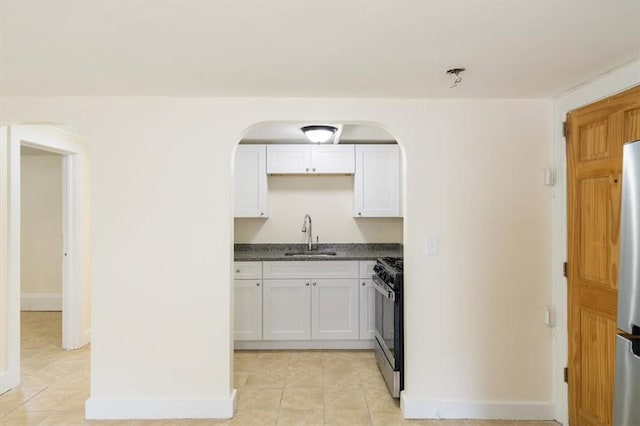 54 Harrison St, Pawtucket, RI 02860 - kitchen featuring dark countertops, appliances with stainless steel finishes, light tile patterned floors, arched walkways, and white cabinets