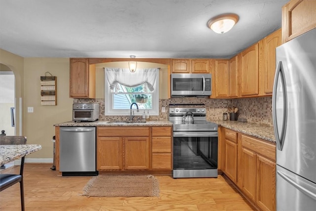 144 Hines Rd, Cumberland, RI 02864 - kitchen with appliances with stainless steel finishes, arched walkways, light wood-type flooring, tasteful backsplash, and light stone countertops