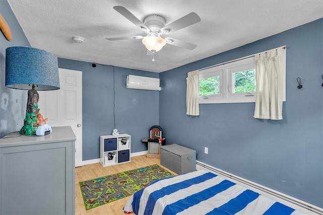 144 Hines Rd, Cumberland, RI 02864 - bedroom featuring a wall mounted air conditioner, light wood-style floors, ceiling fan, and a textured ceiling