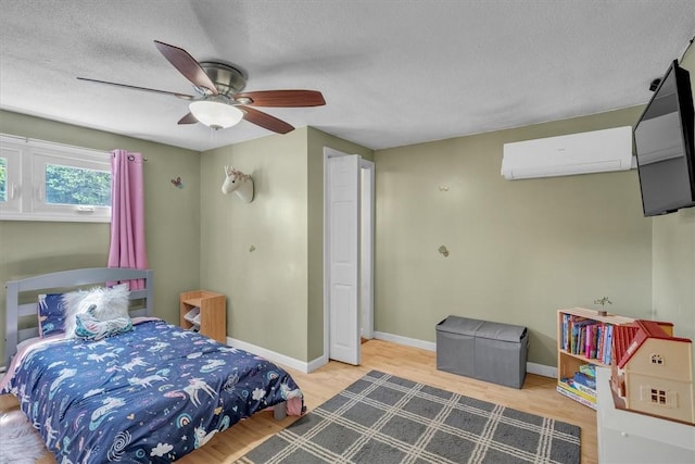 144 Hines Rd, Cumberland, RI 02864 - bedroom with a wall mounted air conditioner, wood finished floors, a textured ceiling, and a ceiling fan