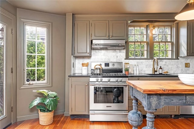 603 E Ave, Pawtucket, RI 02860 - kitchen with stainless steel gas stove, under cabinet range hood, backsplash, wood counters, and light wood-style flooring