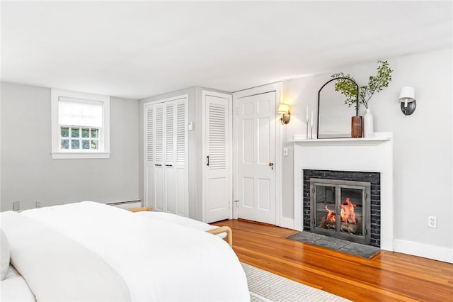 603 E Ave, Pawtucket, RI 02860 - bedroom featuring wood finished floors, multiple closets, a fireplace with flush hearth, and baseboard heating