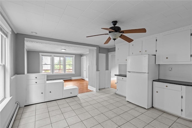289 Mowry St, Woonsocket, RI 02895 - kitchen featuring freestanding refrigerator, baseboard heating, dark countertops, ceiling fan, and white cabinetry