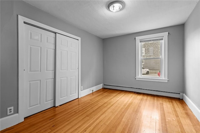289 Mowry St, Woonsocket, RI 02895 - unfurnished bedroom featuring a baseboard heating unit, light wood finished floors, and a closet