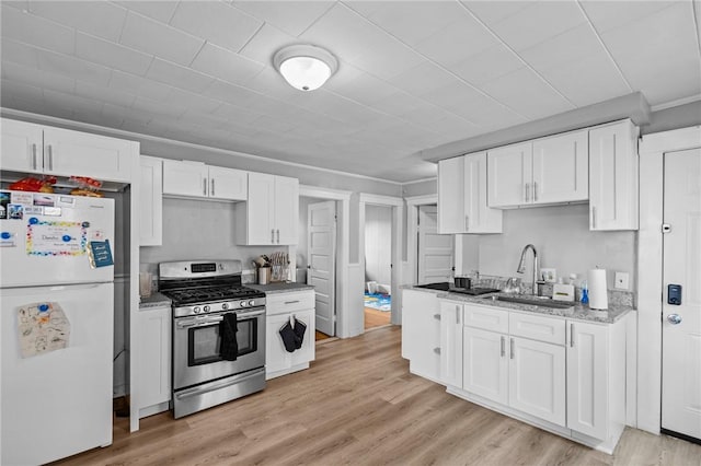 289 Mowry St, Woonsocket, RI 02895 - kitchen with freestanding refrigerator, stainless steel gas stove, white cabinets, light wood finished floors, and crown molding