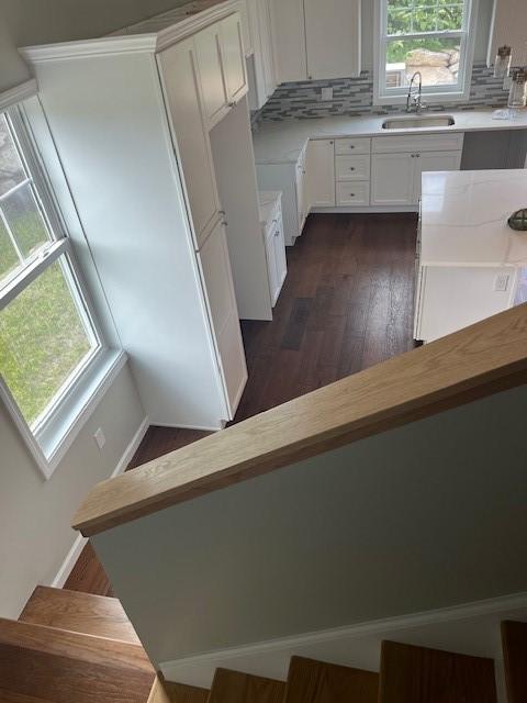 99 Ayda Rose Ave, West Warwick, RI 02893 - kitchen with white cabinetry, light countertops, dark wood-type flooring, and decorative backsplash